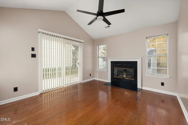 an empty room with windows a fireplace and wooden floor
