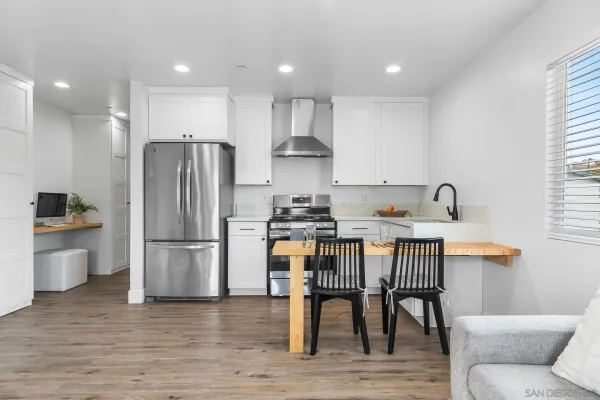a kitchen with stainless steel appliances granite countertop a dining table chairs refrigerator and sink