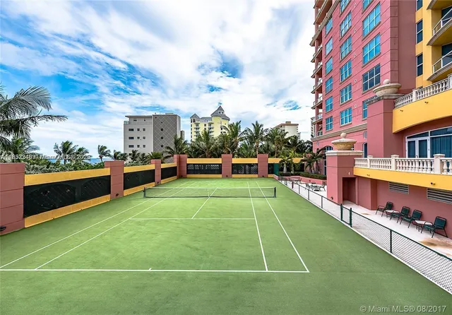 a view of a tennis ground with large trees
