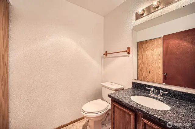 a bathroom with a granite countertop toilet sink and mirror