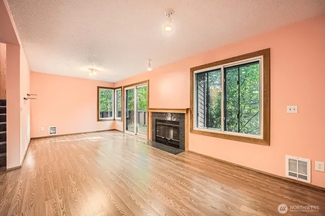 an empty room with windows fireplace and wooden floor
