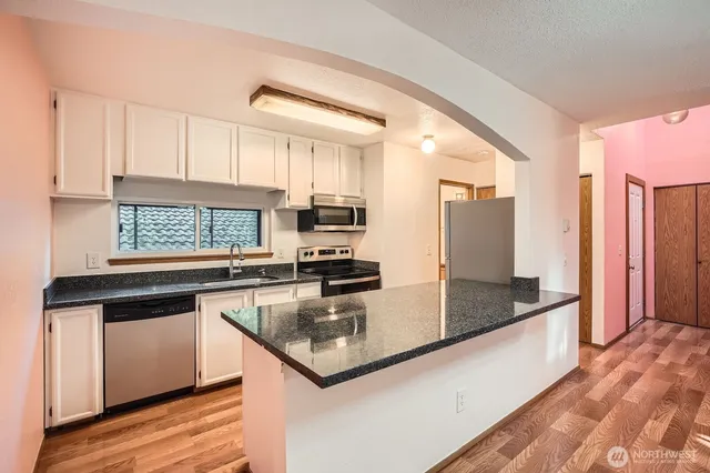 a kitchen with stainless steel appliances granite countertop a sink and dishwasher a stove with wooden floor