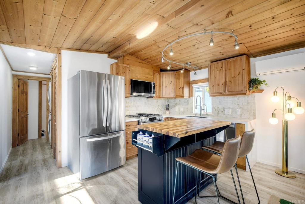 123 Jasper Street, Unit 35 Encinitas, CA 92024 - Photo 17 of 28 a kitchen with stainless steel appliances granite countertop a table chairs refrigerator and microwave