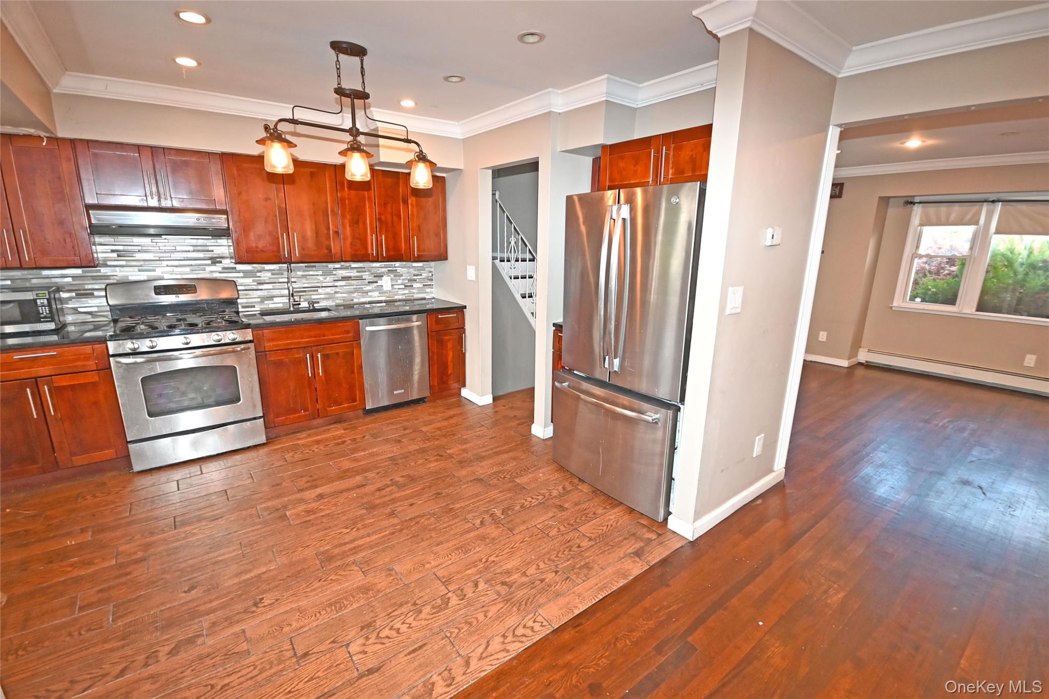 89 Osborne Road West Hempstead, NY 11552 - Photo 35 of 50 Kitchen featuring crown molding, stainless steel appliances, decorative backsplash, pendant lighting, and dark wood-type flooring