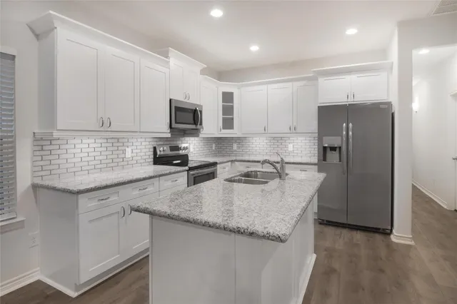 a kitchen with granite countertop a refrigerator a sink a stove a microwave and island