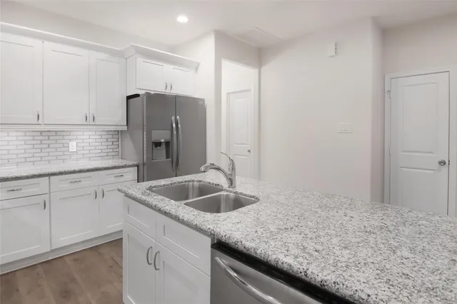 a kitchen with granite countertop a sink and refrigerator