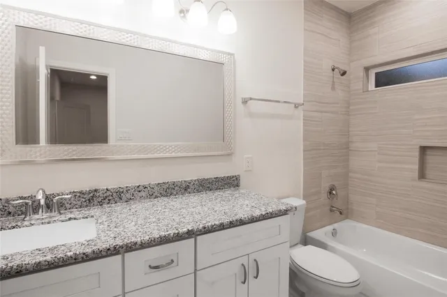a bathroom with a granite countertop sink a toilet and bathtub
