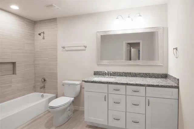 a bathroom with a granite countertop toilet sink and mirror