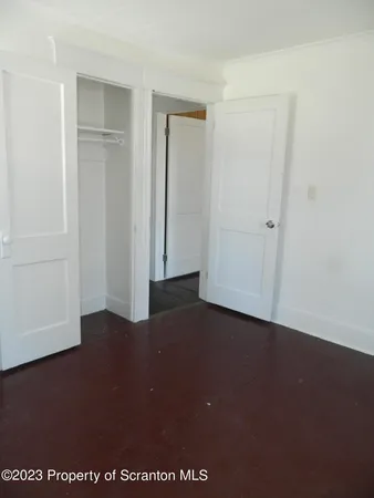 an empty room with wooden floor and windows with curtains