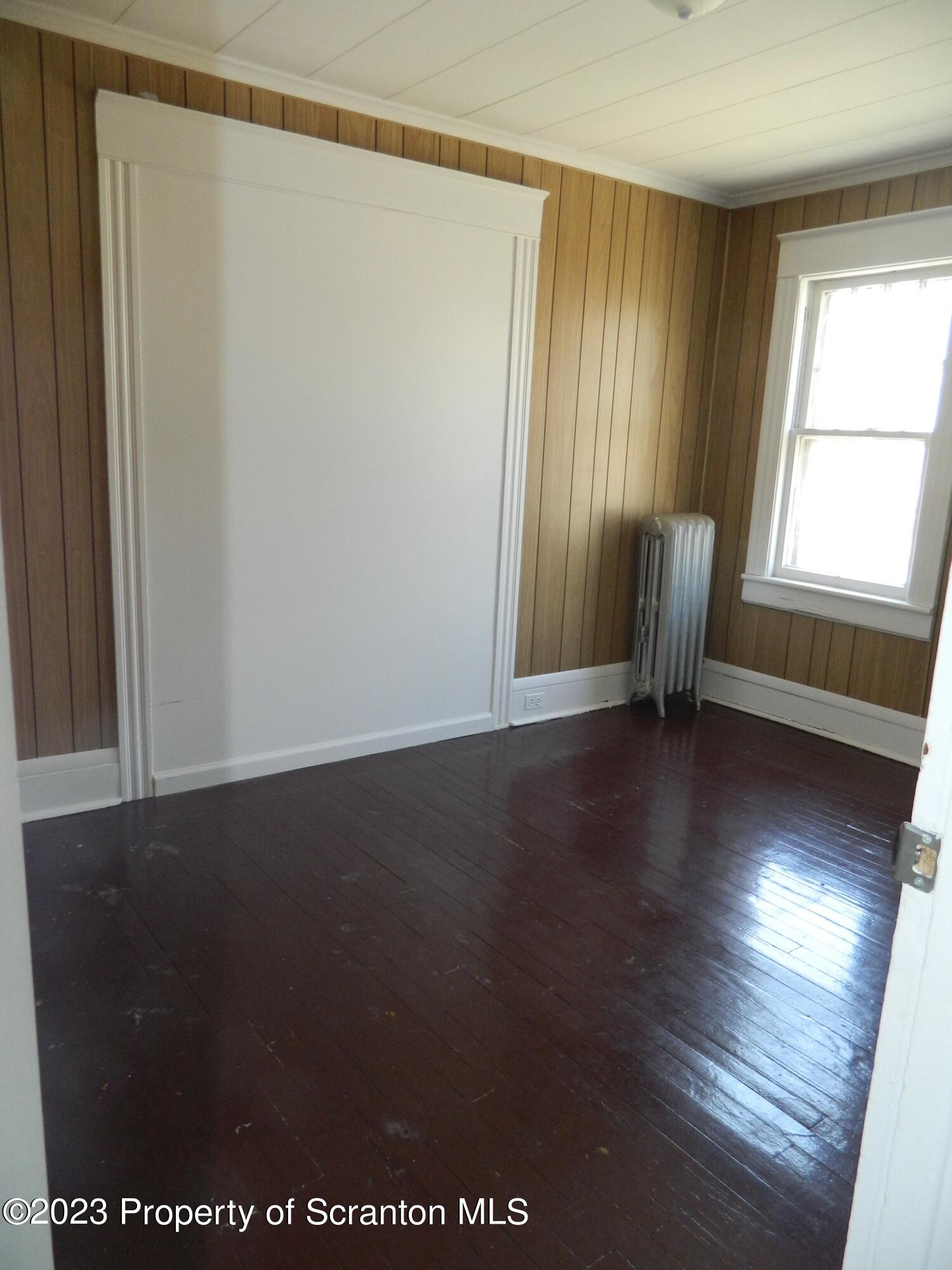 127 East Pine Street Dunmore, PA 18512 - Photo 18 of 20 an empty room with wooden floor and windows with curtains