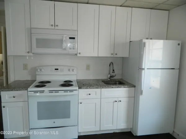 a kitchen with granite countertop white cabinets and refrigerator