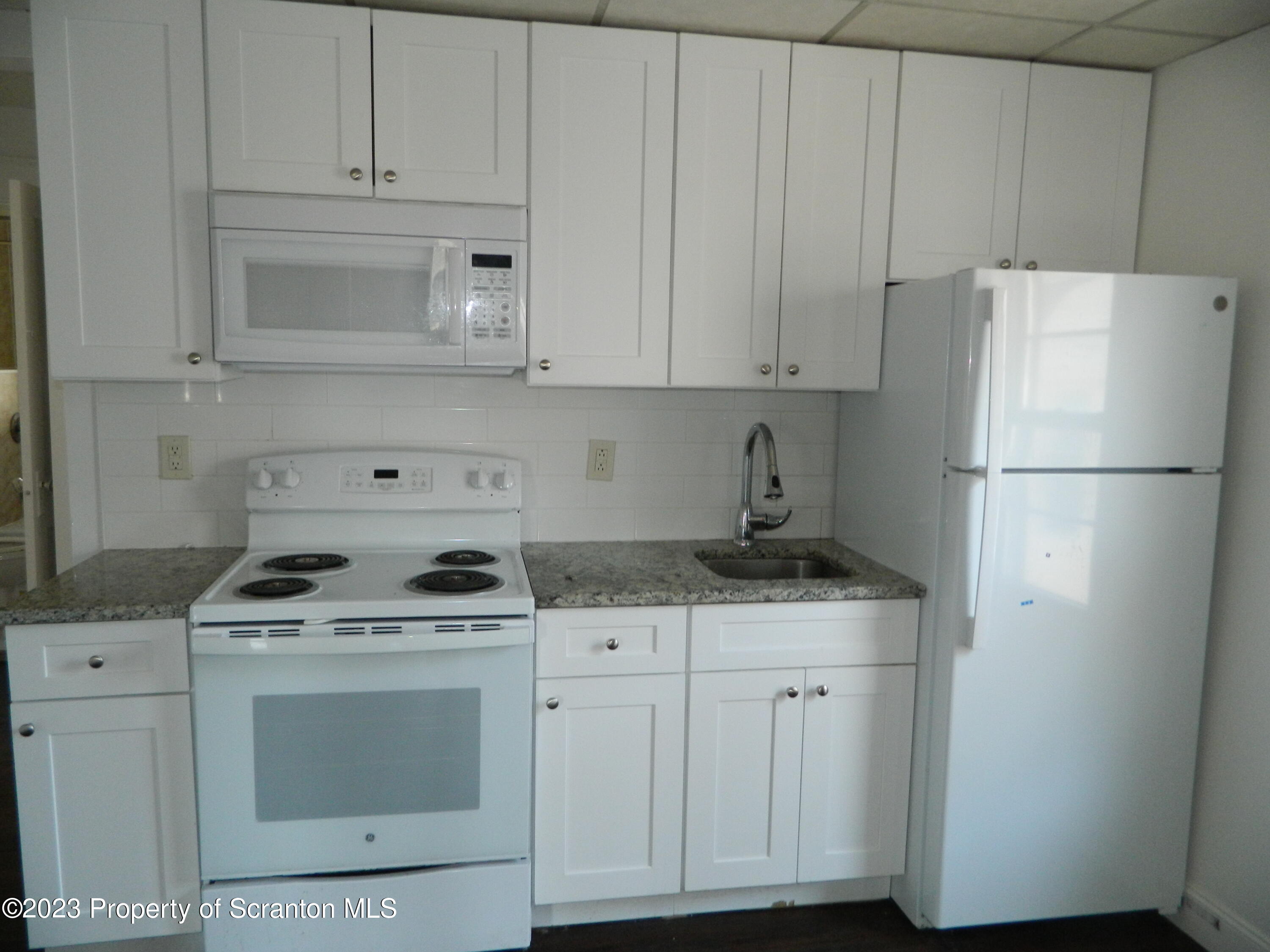 127 East Pine Street Dunmore, PA 18512 - Photo 9 of 20 a kitchen with granite countertop white cabinets and refrigerator