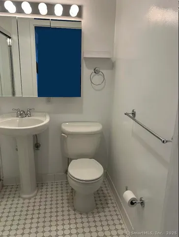 a bathroom with a toilet a sink and mirror