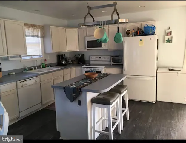 a kitchen with stainless steel appliances granite countertop a refrigerator a stove a sink and white cabinets