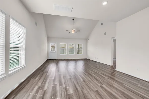 a view of an empty room with wooden floor and a window