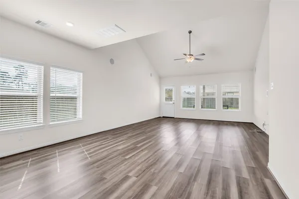 a view of an empty room with wooden floor and a window