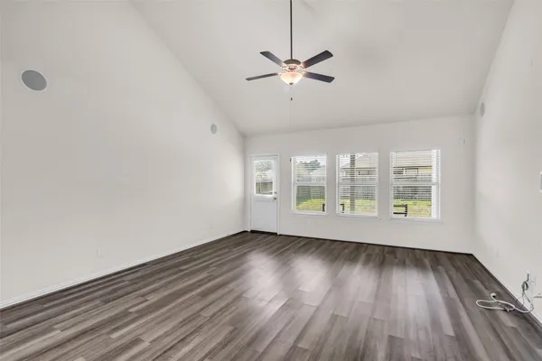 a view of an empty room with wooden floor and a window