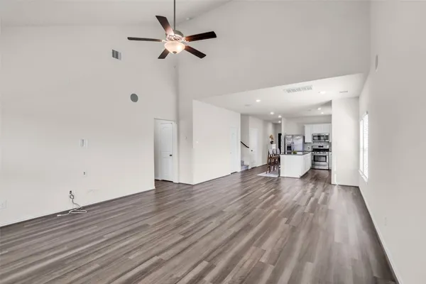 a view of a room with wooden floor and a ceiling fan