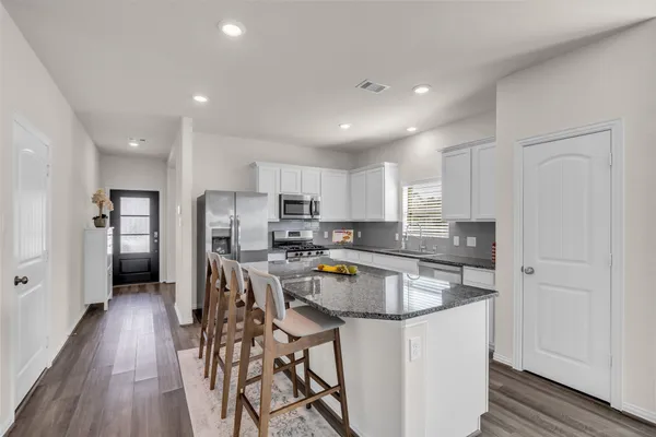 a kitchen with stainless steel appliances a dining table chairs microwave and stove top oven