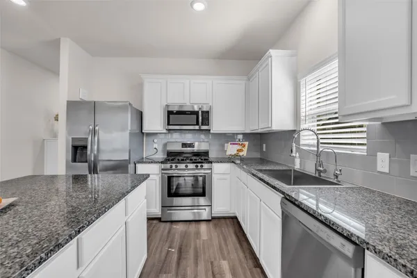 a kitchen with kitchen island granite countertop a sink stove microwave and refrigerator