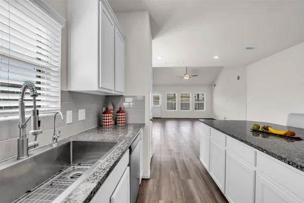 a kitchen with granite countertop a stove sink and cabinets
