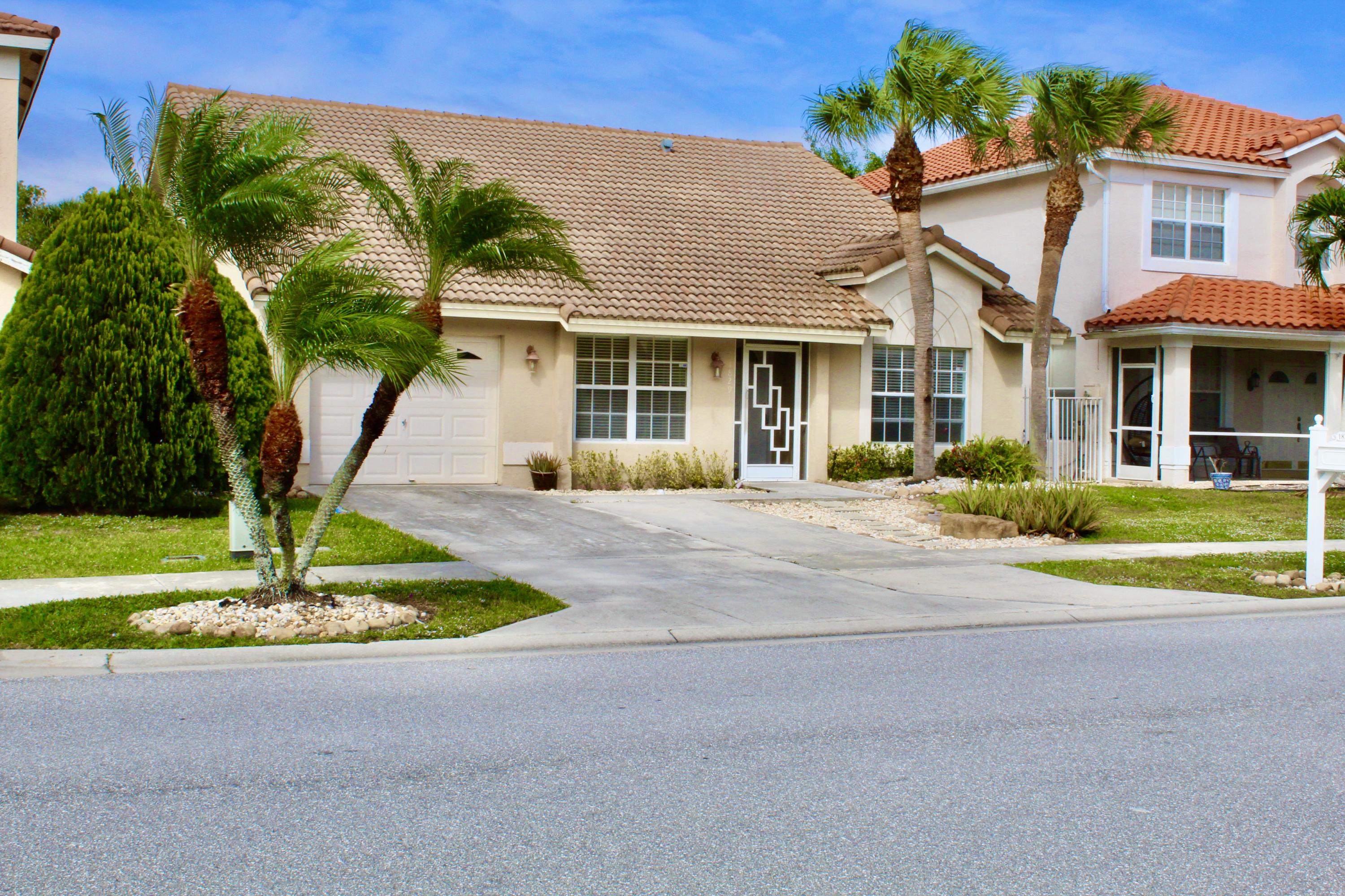 a front view of a house with a yard and palm trees