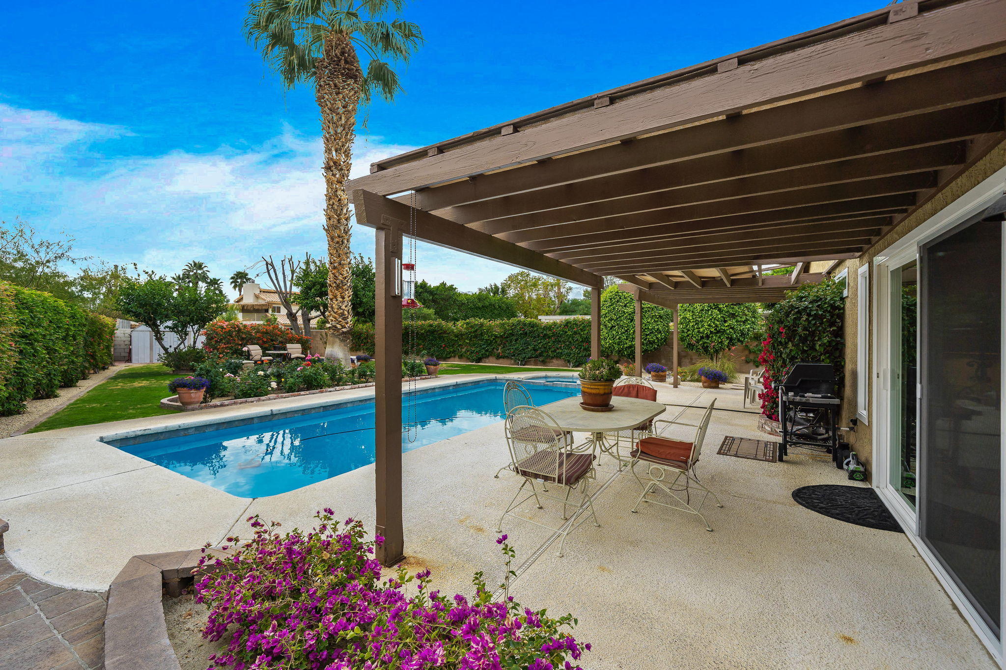 68435 Durango Road Cathedral City, CA 92234 - Photo 14 of 41 a view of a patio with couches table and chairs under an umbrella with a small yard
