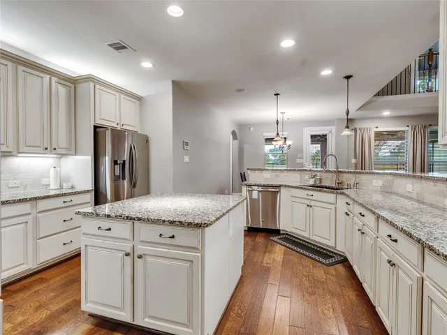 a kitchen with granite countertop white cabinets and stainless steel appliances