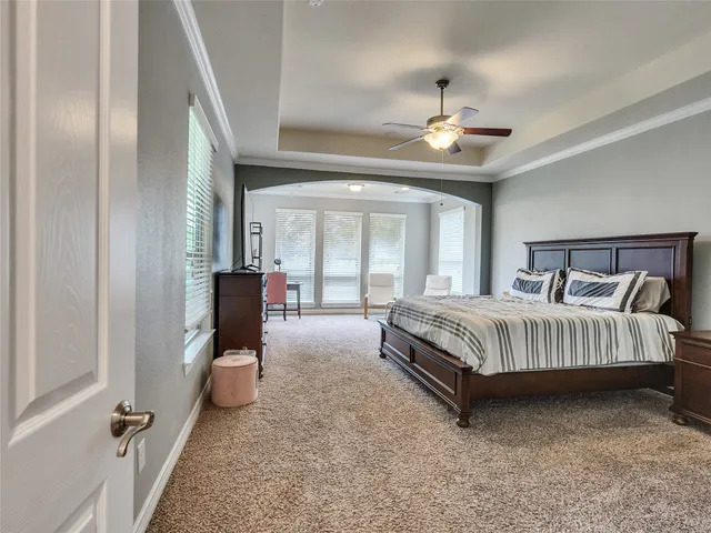 a spacious bedroom with a bed couch chandelier and a window