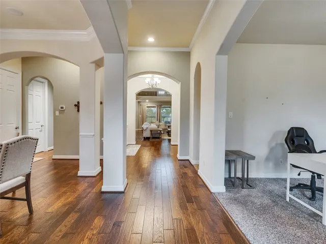 a view of a hallway with wooden floor table and chairs
