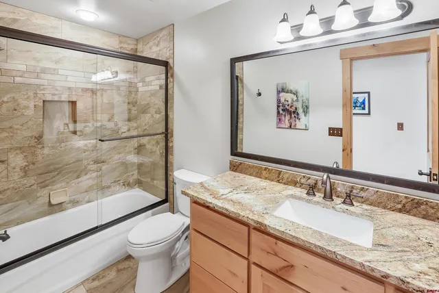 a bathroom with a granite countertop sink mirror vanity and toilet
