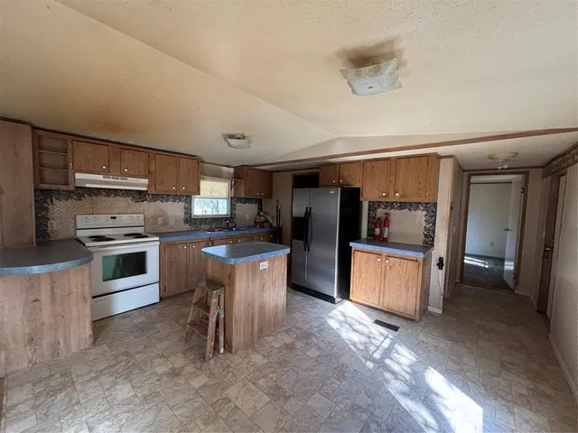 a kitchen with stainless steel appliances kitchen island granite countertop a refrigerator and stove top oven