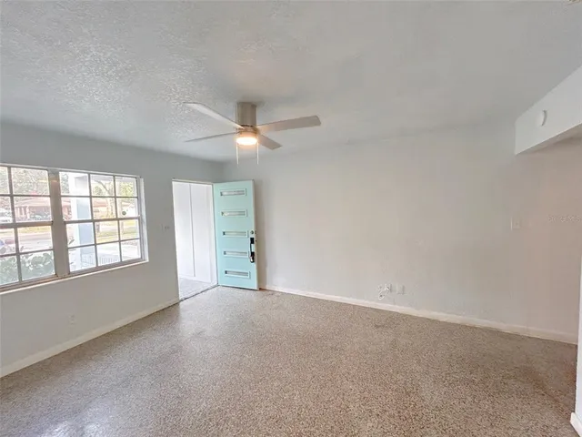 an empty room with windows and chandelier fan