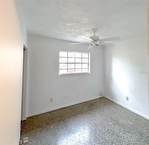 an empty room with a window and a fan
