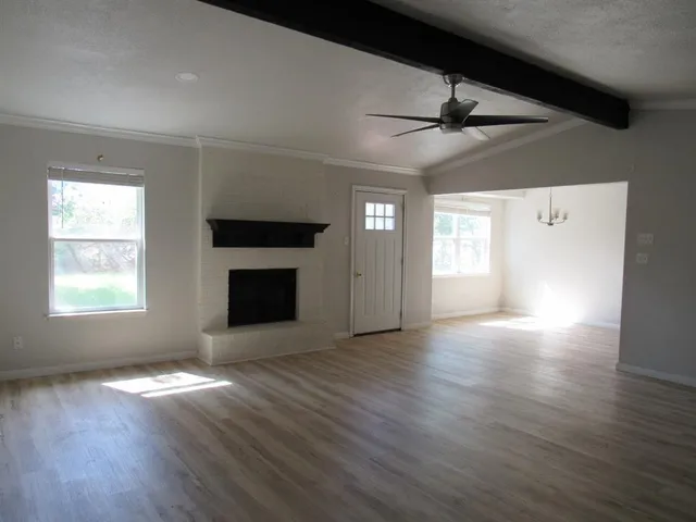 an empty room with wooden floor fireplace and windows