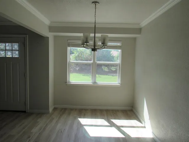 a view of a room with window wooden floor and front door