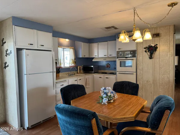 a kitchen with stainless steel appliances granite countertop a refrigerator a sink a stove a dining table and chairs