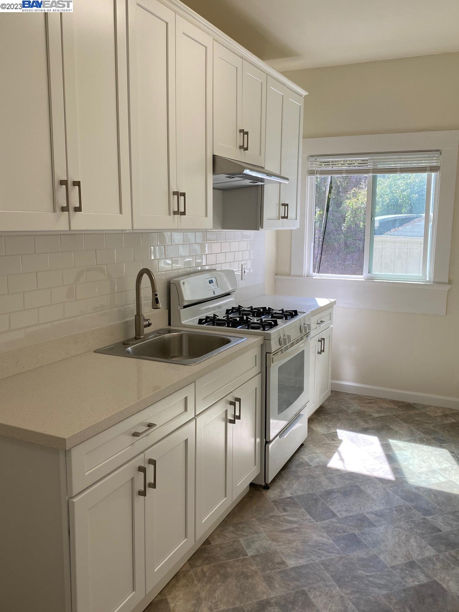 Ivy Hill Oakland, CA 94606 - Photo 5 of 19 a white kitchen with granite countertop a stove a sink and white cabinets