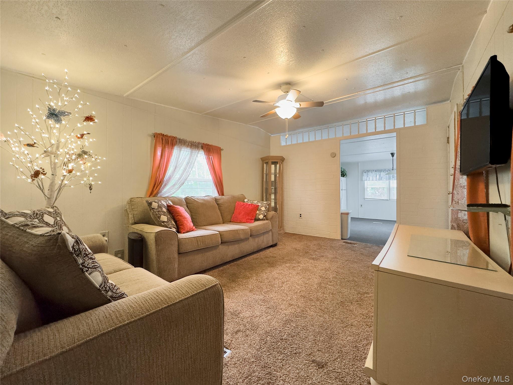 1964 River Road, Unit 55 Calverton, NY 11933 - Photo 5 of 13 a living room with furniture and a flat screen tv