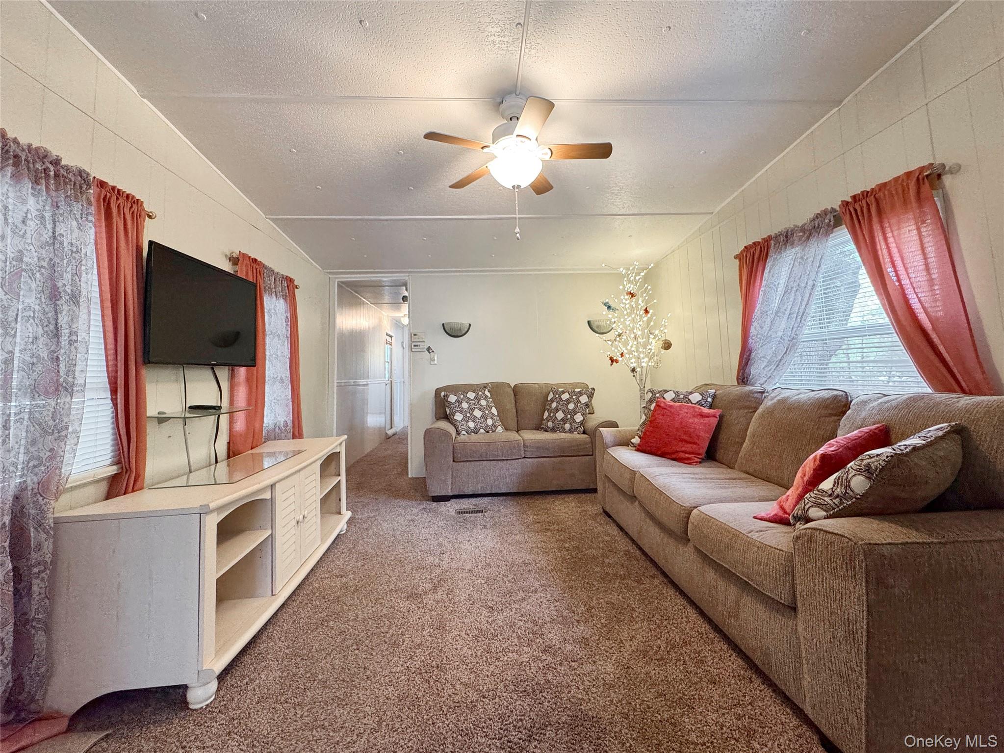1964 River Road, Unit 55 Calverton, NY 11933 - Photo 6 of 13 a living room with furniture and a flat screen tv