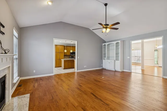 a view of an empty room with a window and wooden floor
