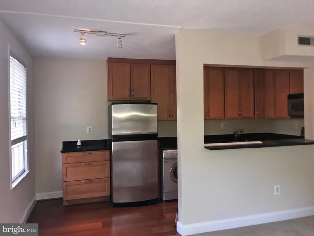 a kitchen with stainless steel appliances granite countertop a refrigerator a stove and a microwave with wooden floor