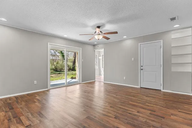 a view of an empty room with a window and wooden floor
