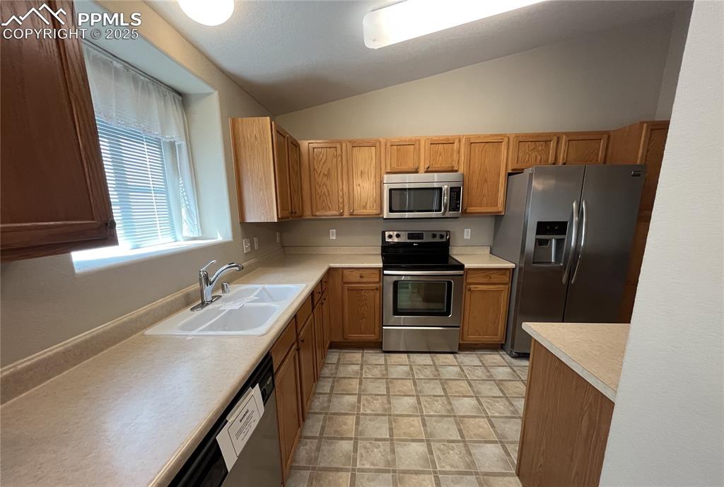 3927 Riviera Grove, Unit 203 Colorado Springs, CO 80922 - Photo 6 of 16 a kitchen with a sink a microwave a refrigerator and cabinets