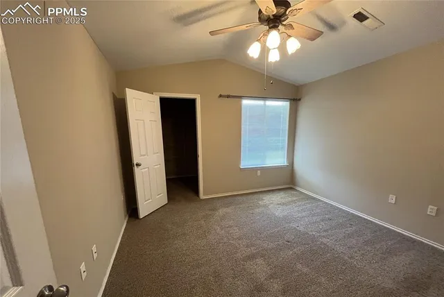 an empty room with closet and a chandelier fan