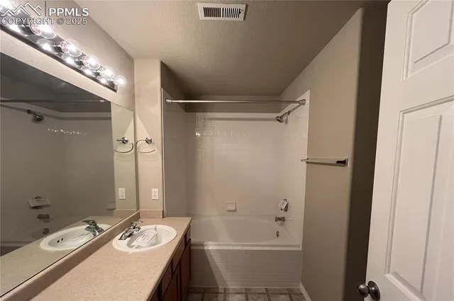 a bathroom with a granite countertop sink a mirror and shower