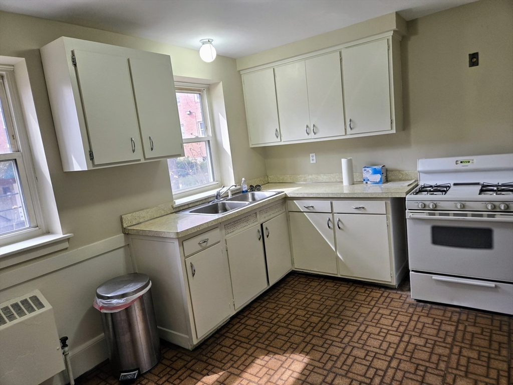 465 Arborway, Unit 13 Boston, MA 02130 - Photo 11 of 41 a kitchen with a sink stove and cabinets