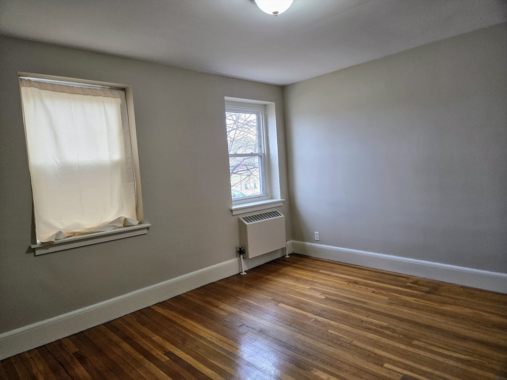465 Arborway, Unit 13 Boston, MA 02130 - Photo 25 of 41 an empty room with wooden floor and windows