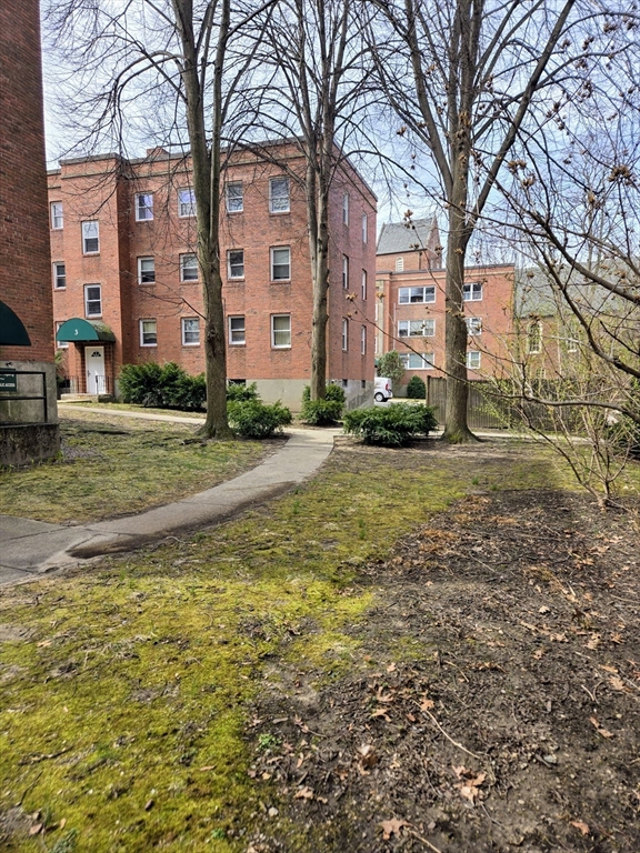 465 Arborway, Unit 13 Boston, MA 02130 - Photo 5 of 41 a view of a big building with a big yard and large trees