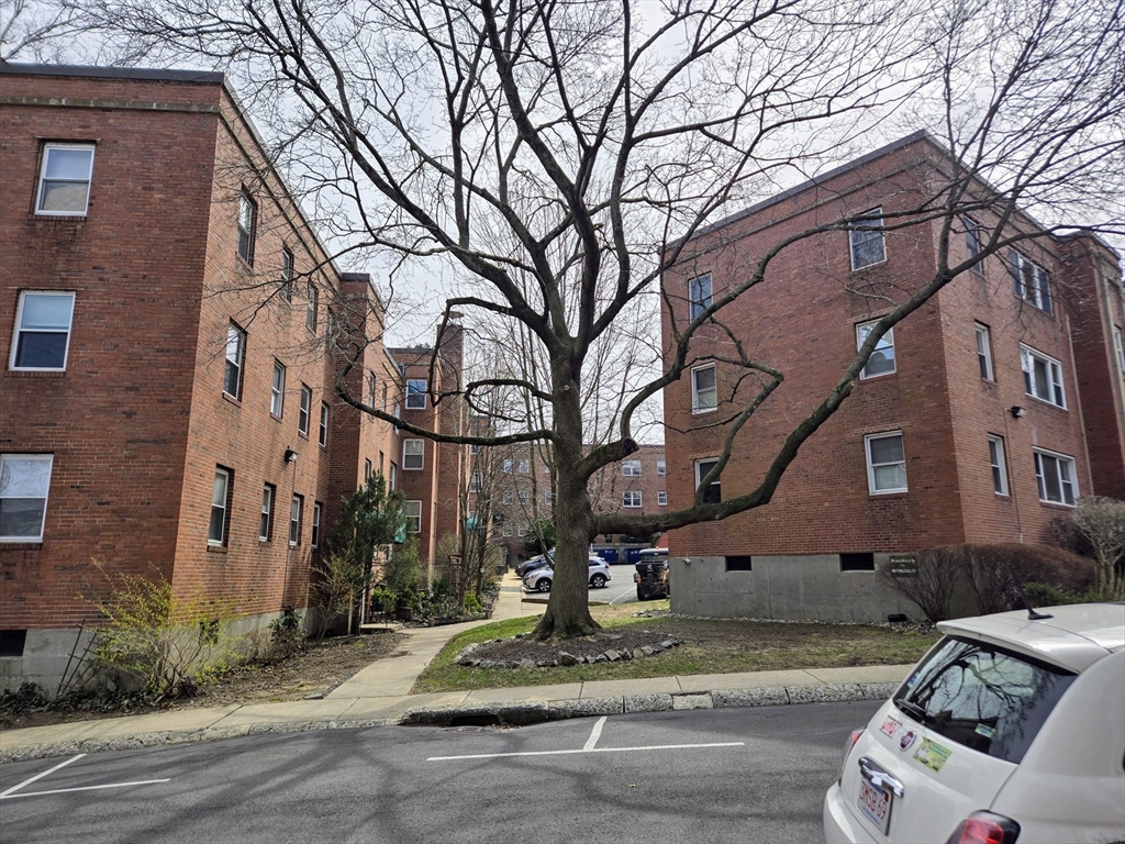465 Arborway, Unit 13 Boston, MA 02130 - Photo 7 of 41 a front view of a building with garden and trees